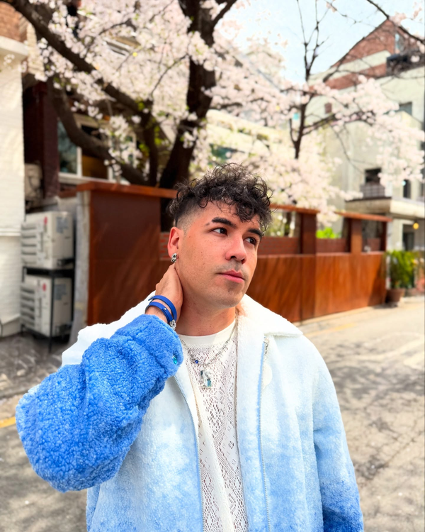 Person wearing a blue jacket with cherry blossom trees in the background